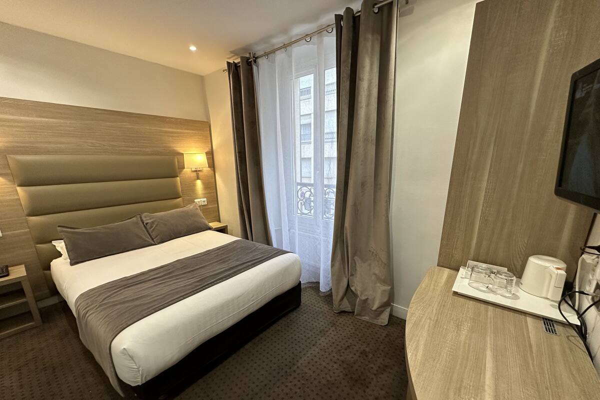 A hotel room with a large bed, a desk with a coffee maker, and a TV.