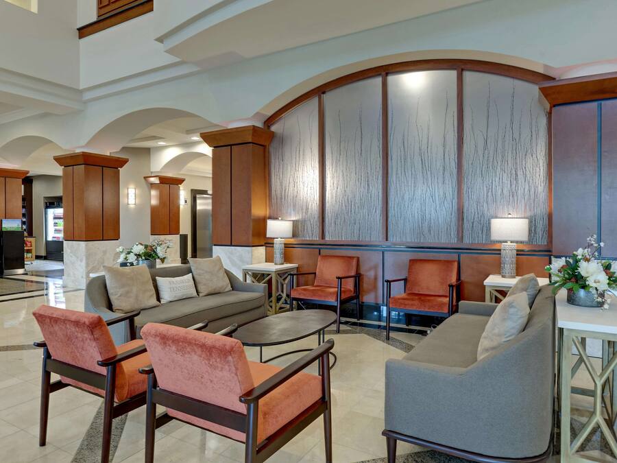 A spacious lobby with a curved wall, seating area with sofas and chairs, and a reception desk.
