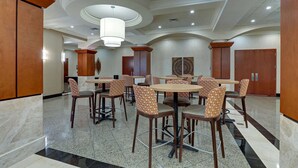 A spacious dining area with round tables and patterned chairs, featuring a polished marble floor and wooden accents.