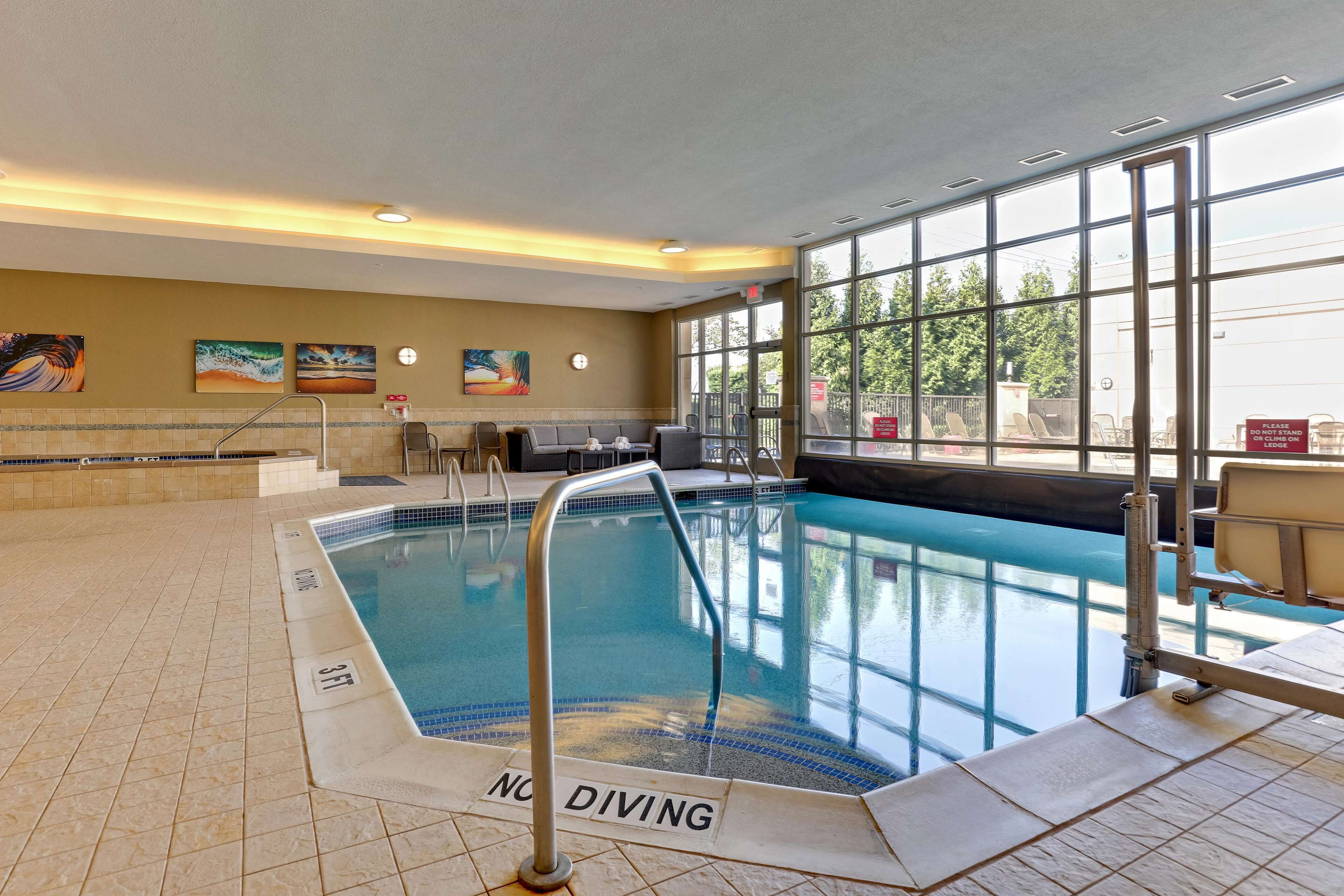 An indoor swimming pool with a 'No Diving' sign, tiled floor, and artwork on the walls.
