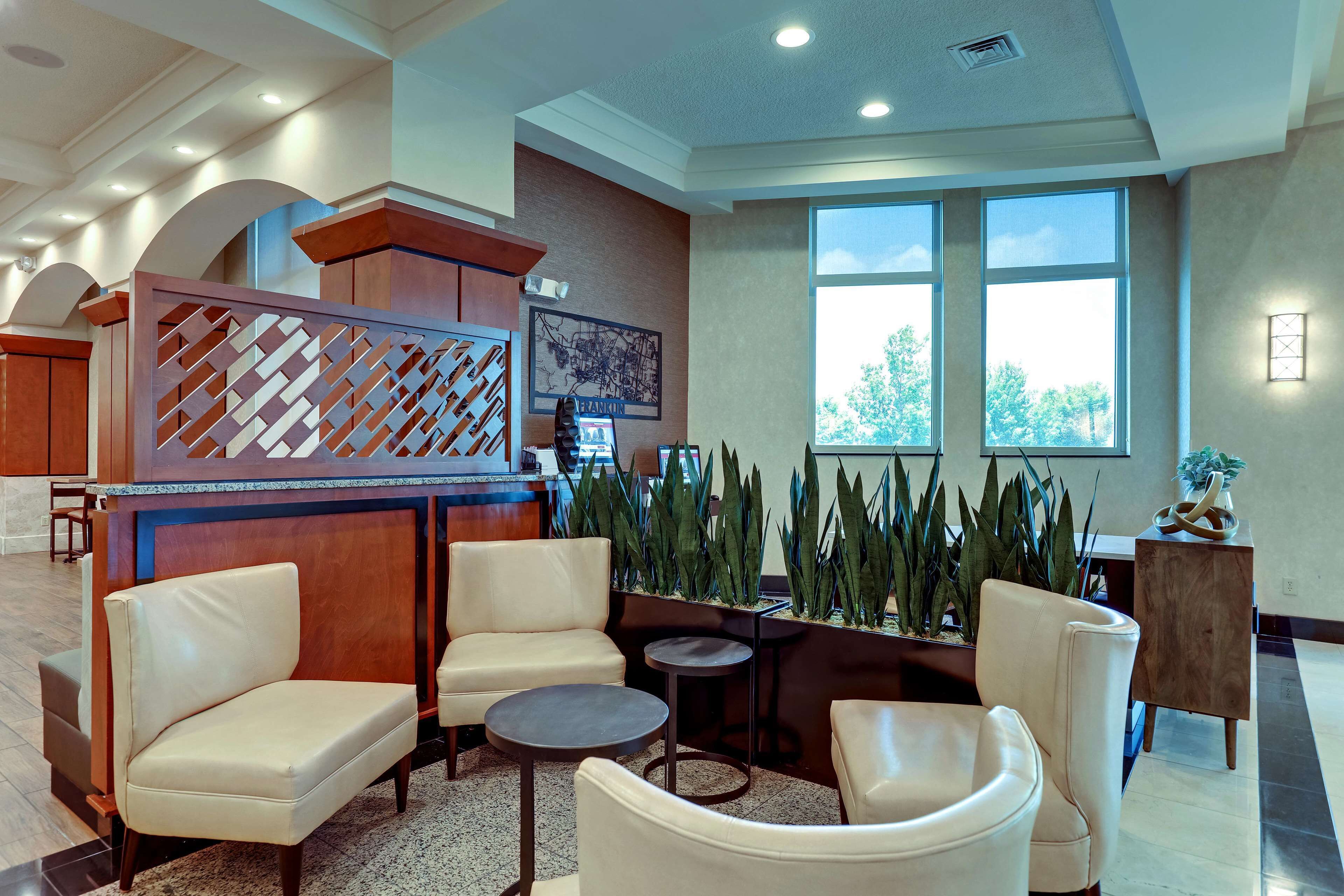 A lobby with seating, a reception desk, and large windows.