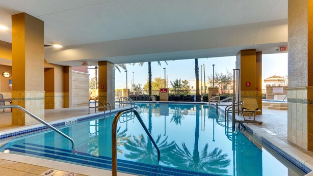 An indoor swimming pool with clear blue water, surrounded by beige walls and a tiled floor.