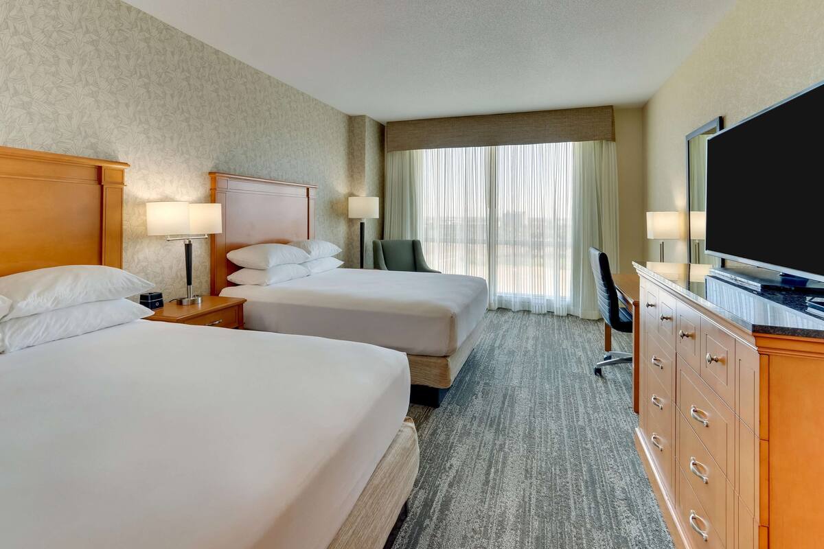 A hotel room with two beds, a TV, a desk, and a dresser.