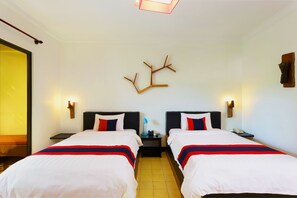 Ein Hotelzimmer mit zwei Betten, einem Nachttisch, einer Wandlampe und einem Holzdekor.