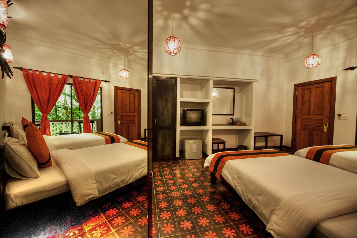 Ein Hotelzimmer mit zwei Betten, einem Fernseher, einem kleinen Tisch und einer Ablage mit Gegenständen.
