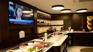 Un ristorante con una televisione che mostra un notiziario, un buffet con diversi piatti e un'area bar.