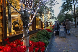 En restaurang med uteservering, dekorerad med ljusslingor och röda blommor.