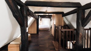 A narrow, wooden staircase with exposed beams leading to a bedroom with a bed and a window. - Kulturbrauerei Heidelberg AG (Heidelberg)