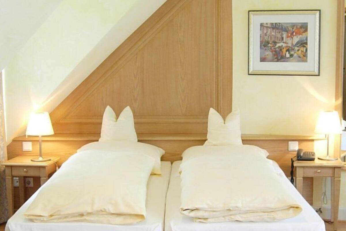 A room with two beds, wooden headboards, and a sloped ceiling.
