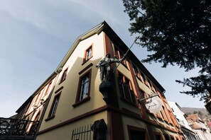A building with a statue on the corner, a clock, and a sign with a coat of arms. - Kulturbrauerei Heidelberg AG (Heidelberg)