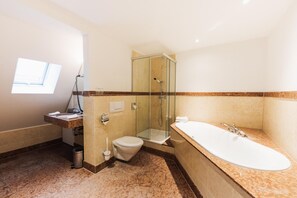 A modern bathroom with a glass-enclosed shower, a freestanding bathtub, and a toilet. - Kulturbrauerei Heidelberg AG (Heidelberg)