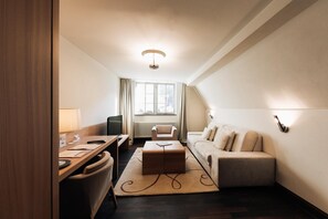 A modern hotel room with a dining area, a sofa, a coffee table, and a TV. - Kulturbrauerei Heidelberg AG (Heidelberg)