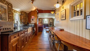 A kitchen with wooden cabinets, a bar area with stools, and a stone wall. - Clenaghans (Craigavon)