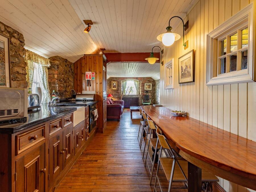 Eine Küche mit Holzausstattung, einer Bar mit Barhocker und einer Wand aus Stein.