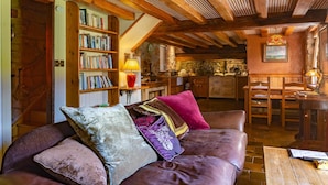 A cozy living room with a wooden ceiling, a bookshelf, a fireplace, and a dining area with wooden furniture. - Clenaghans (Craigavon)