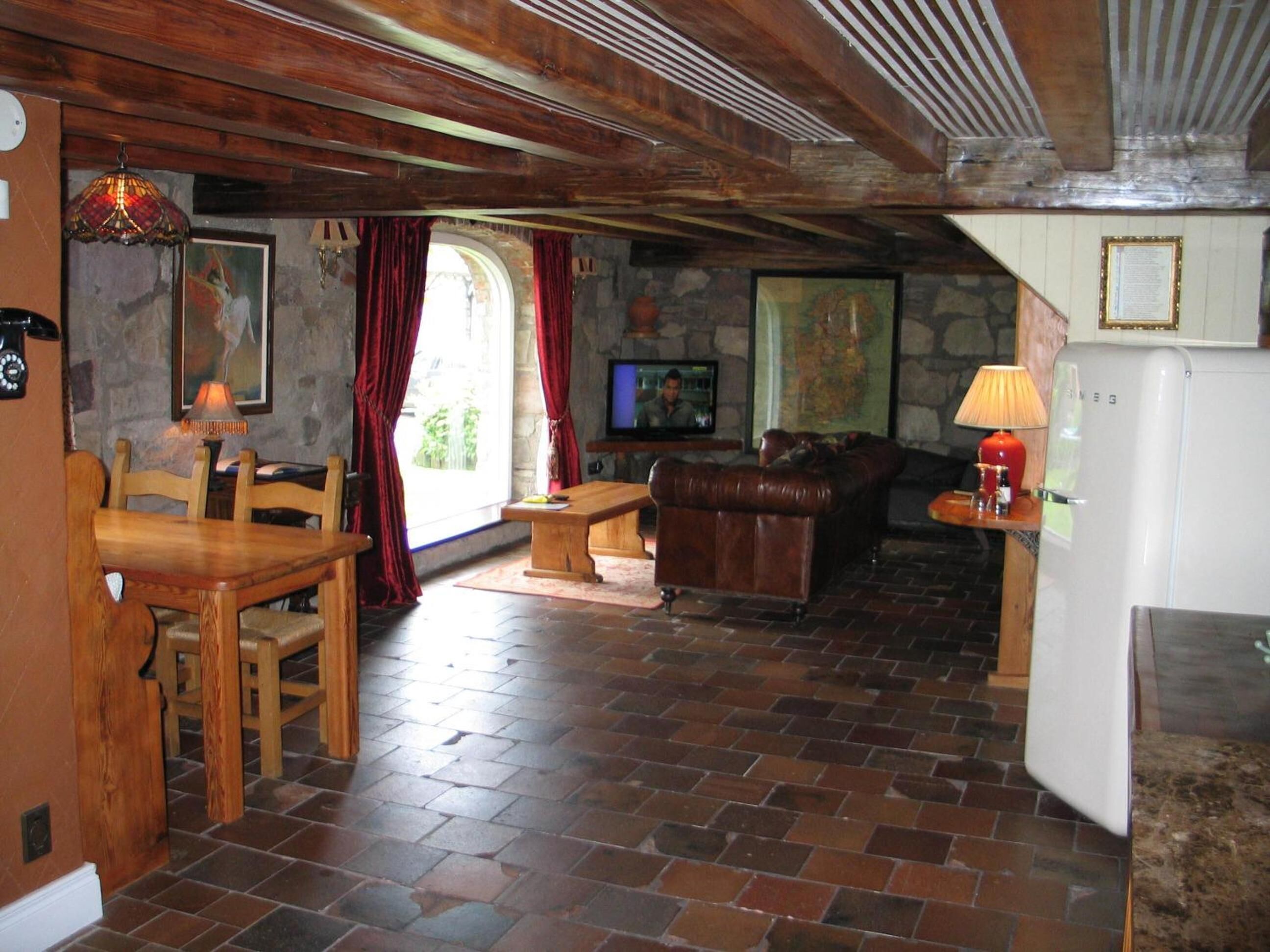 A rustic interior with a stone wall, wooden furniture, a television, and a refrigerator.