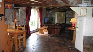 A rustic interior with a stone wall, wooden furniture, a television, and a refrigerator.