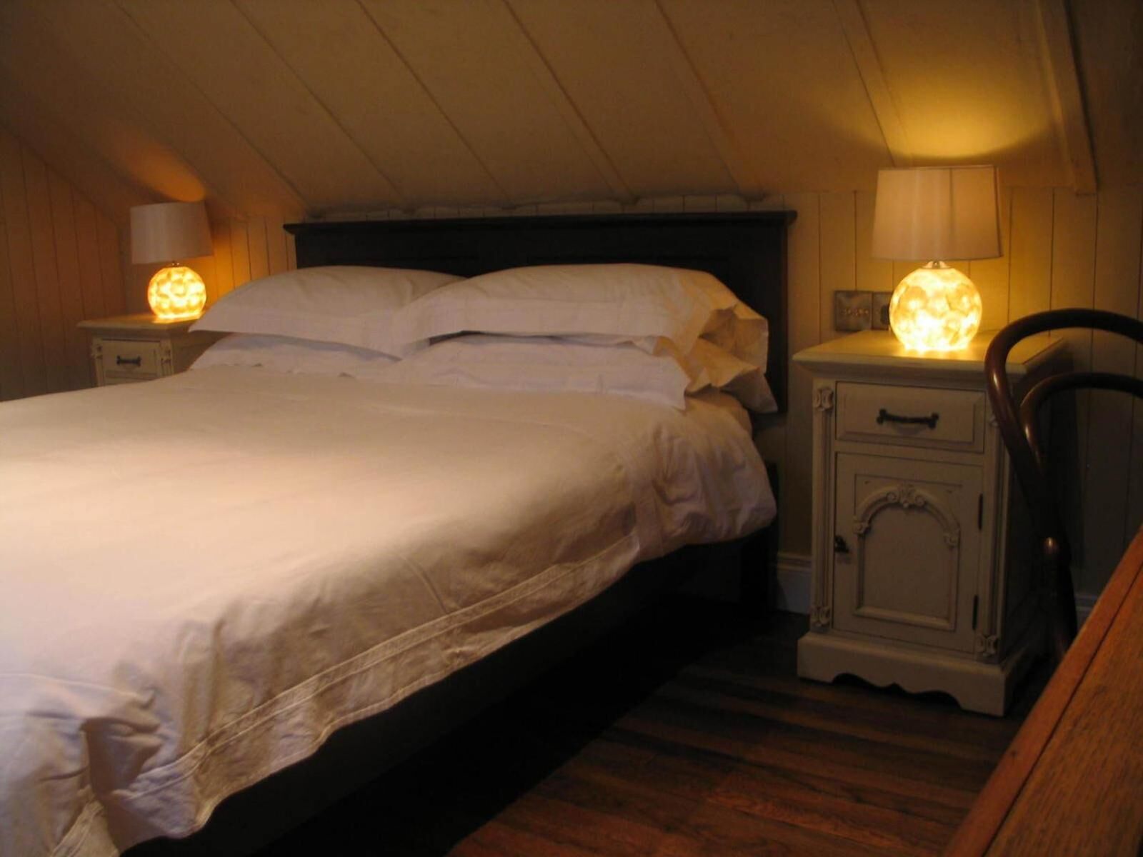Um quarto com uma cama, mesas de cabeceira e um criado-mudo.