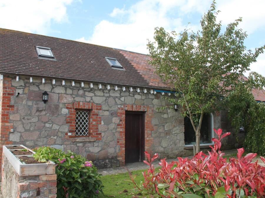 A stone building with a tiled roof, a small window, and a door.