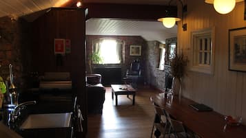 A cozy room with a wooden floor, a dining table, chairs, a sofa, and a fireplace.