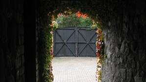 A stone archway leading to a paved courtyard with a metal gate. - Clenaghans (Craigavon)