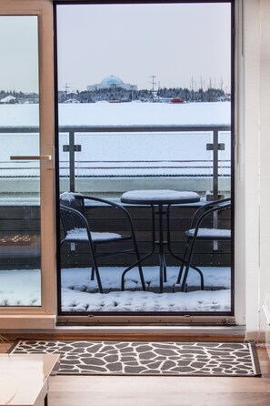 Uitzicht vanaf een balkon met een met sneeuw bedekte grond, een houten tafel en twee stoelen.