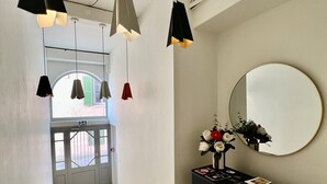 A hallway with a marble floor, a black console table with a mirror, and pendant lights. - Hôtel Posta Vecchia (Bastia)