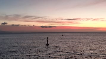 Mar tranquila al atardecer, con una boya y un barco a lo lejos.