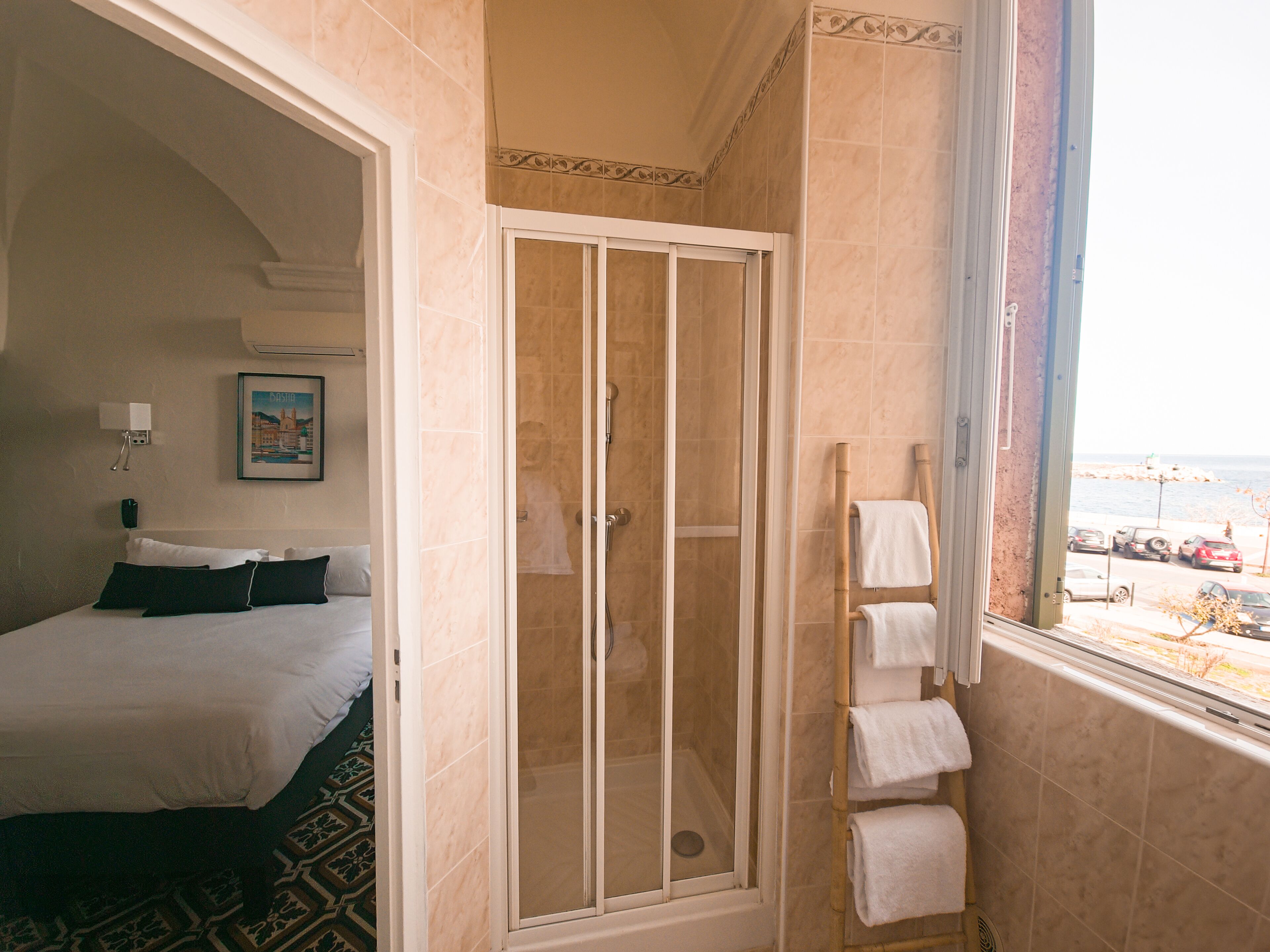 Une chambre d’hôtel avec un lit, une douche et vue sur la mer.