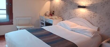 Une chambre à coucher comprenant un lit, une table de chevet, une chaise et une œuvre d’art accrochée au mur.