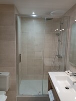 A modern bathroom with a glass-enclosed shower, a white sink, and a mirror.