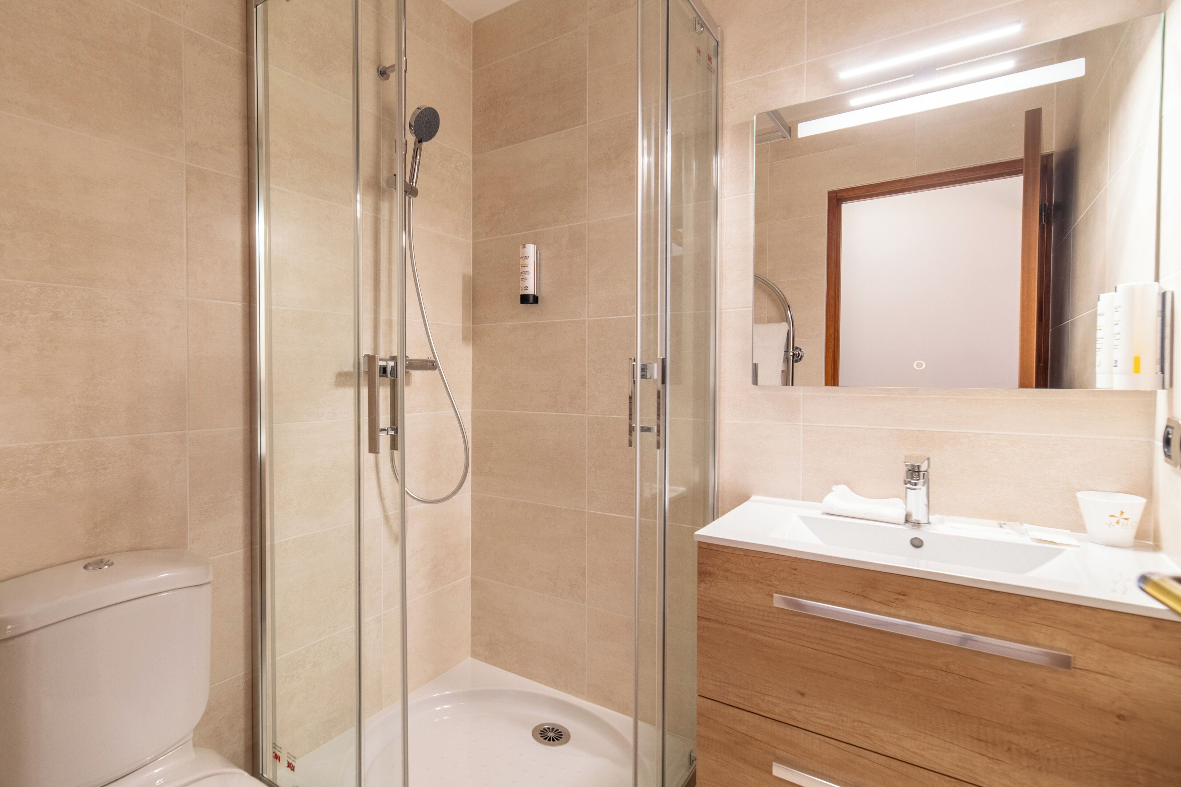 Une salle de bain moderne avec une douche à parois de verre, un lavabo blanc et un meuble-lavabo en bois.