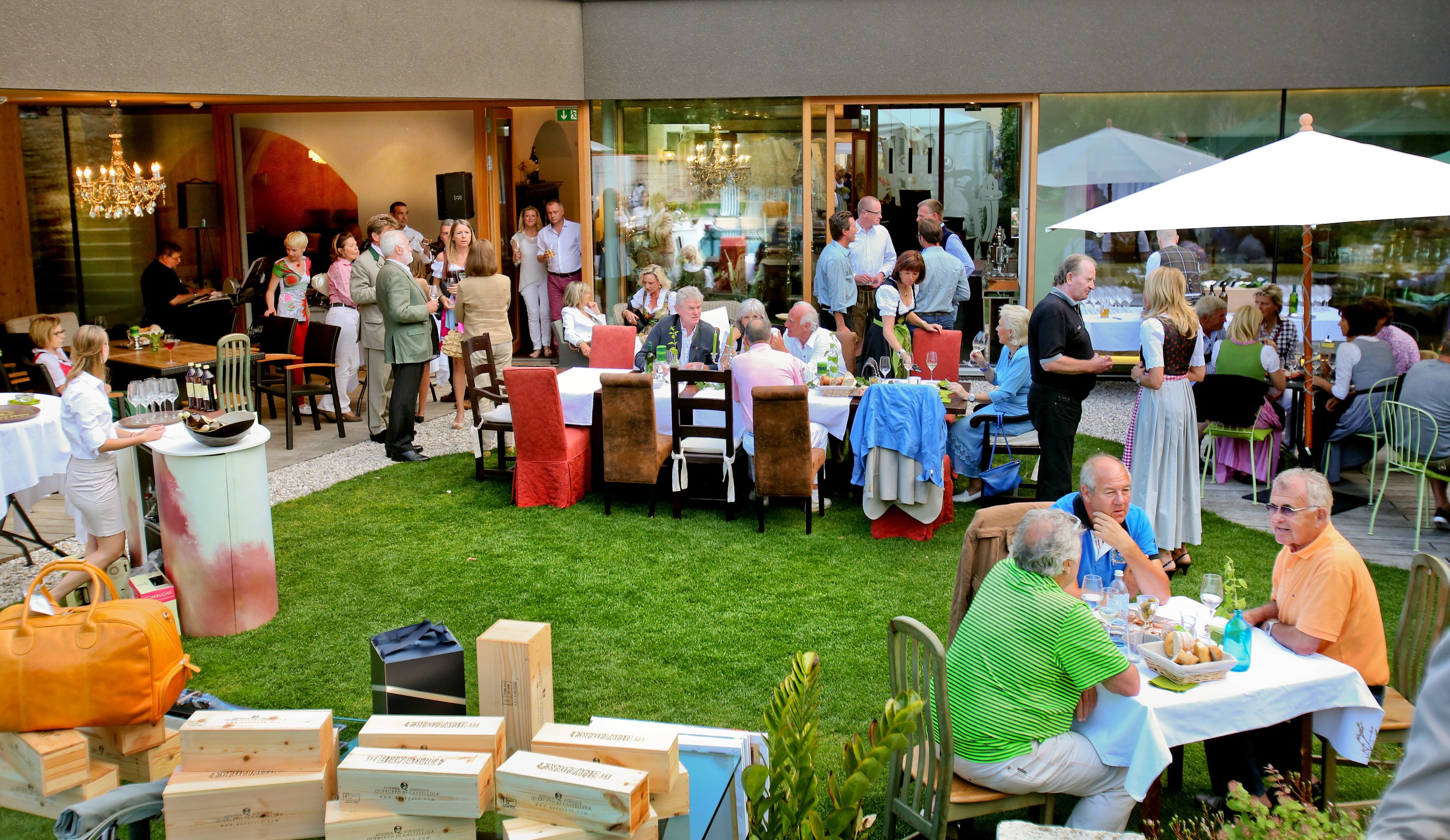 An outdoor dining area with tables and chairs, surrounded by a grassy lawn.