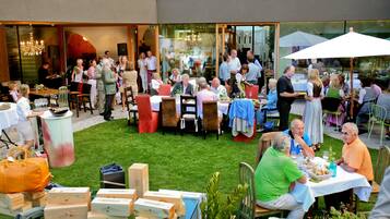 An outdoor dining area with tables and chairs, surrounded by a grassy lawn.