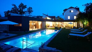 A modern house with a swimming pool, outdoor seating, and a well-lit patio area. - Hotel Landhaus Moserhof (Gumpoldskirchen)