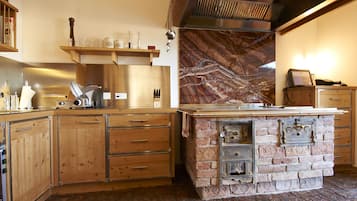A kitchen with wooden cabinets, a brick stove, and a marble backsplash.