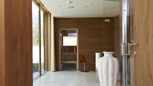A modern interior with a wooden floor, a large white vase, and a glass door leading to another room. - Hotel Landhaus Moserhof (Gumpoldskirchen)