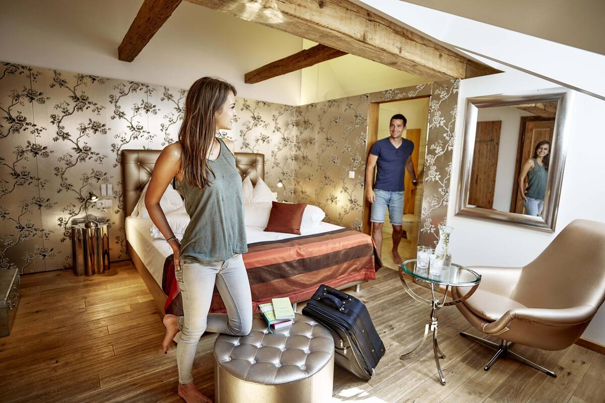Ein Schlafzimmer mit einem Bett, einem Glastisch, einem Stuhl und einem Koffer.