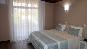Un dormitorio con cama, cortinas, lámpara de noche y mesita de noche.