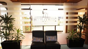 Un hall de hotel con dos sillones de cuero negro, un letrero que dice "HOTEL CONTRIZ" y plantas en macetas.