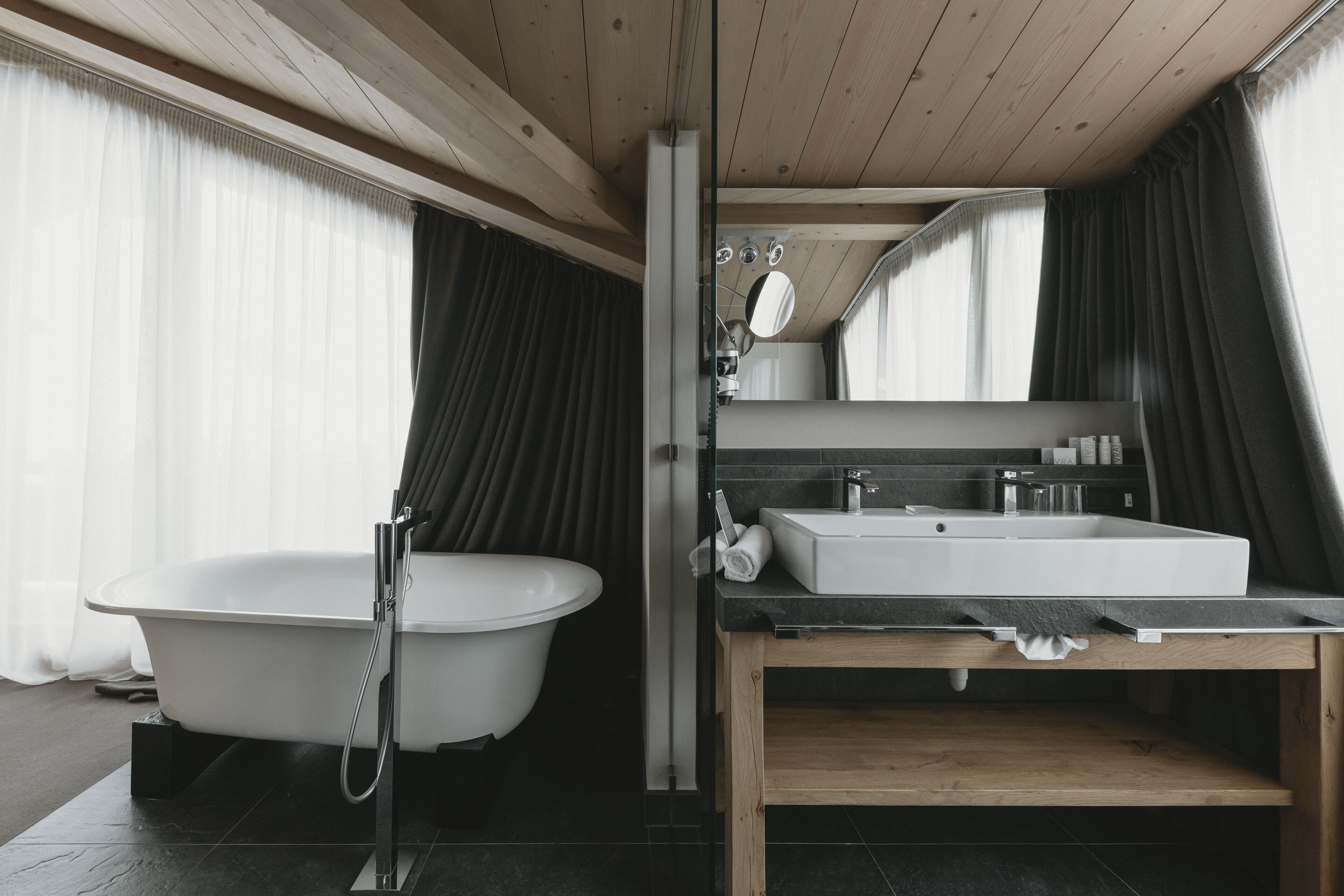 Un baño moderno con una bañera independiente, un lavabo y un espejo sobre él.