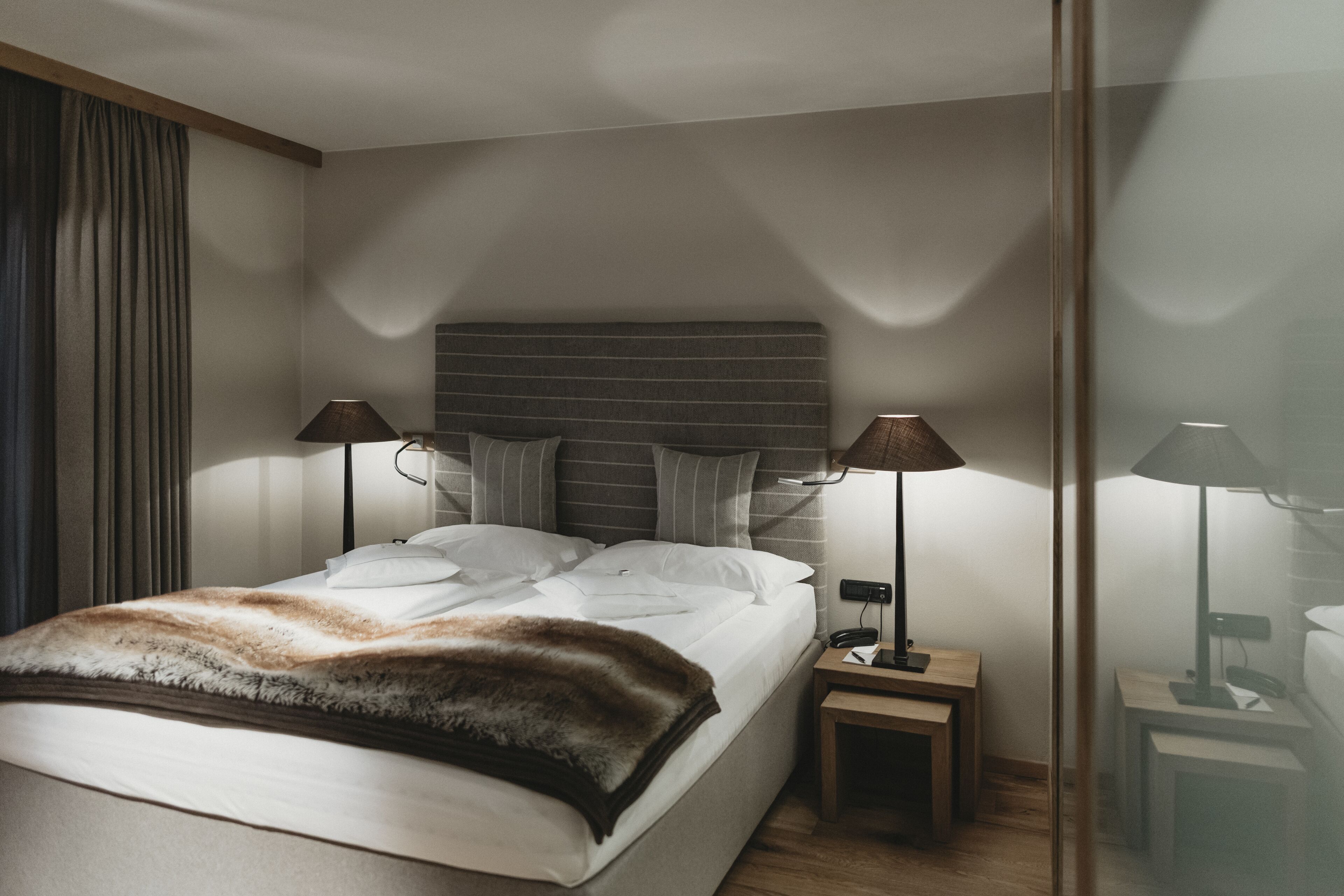 Een moderne hotelkamer met een groot bed, twee nachtkastjes en een hoofdeinde.