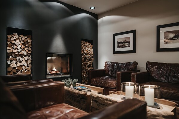 A cozy living room with a fireplace, leather sofas, and framed pictures on the wall. - Eco & Wellness Boutique Hotel Sonne (Livigno)