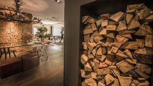 A modern interior with a stone wall, a wooden sculpture, and a stack of firewood. - Eco & Wellness Boutique Hotel Sonne (Livigno)