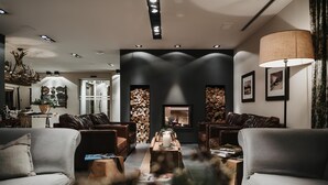 A modern living room with leather sofas, a glass coffee table, and a fireplace. - Eco & Wellness Boutique Hotel Sonne (Livigno)