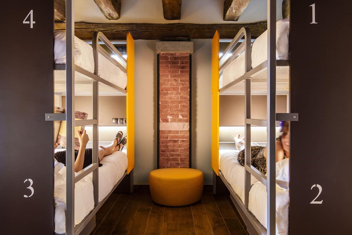 A hotel room with bunk beds, numbered doors, and a brick wall.