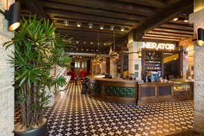 Una zona de bar con mostrador, una planta grande en maceta y suelo estampado.