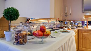 A buffet table with various food items, including fruits and pastries, and a potted plant. - Hotel Schlossblick (Wernigerode)