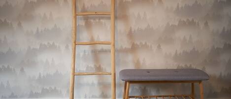 A wooden ladder and a bench against a wallpapered wall.