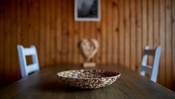 Una mesa de madera con un cuenco tejido en el centro, rodeada por sillas blancas.